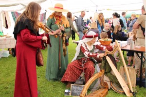 Festival attendees crowd into a craft tent to investigate medieval music,  butter churning, and wool weaving.