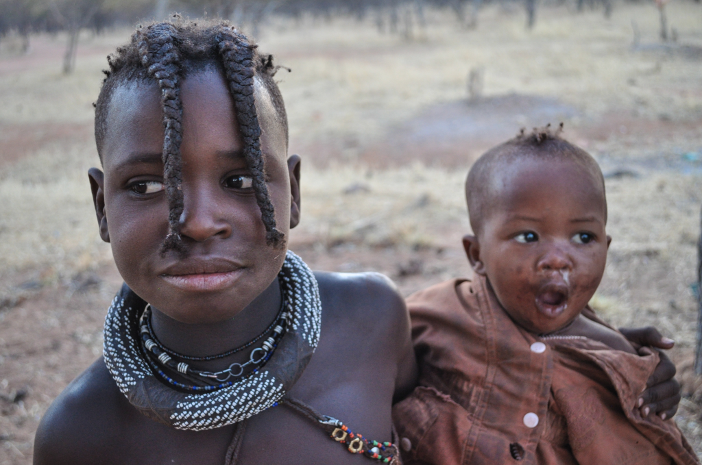 A Himba girl in Namibia carries a baby through the village. Photo by Victoria Nechodomu