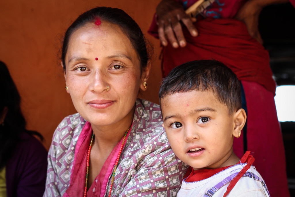 A young girl sits with her mother during a JWAC women's group meeting. Photo by Victoria Nechodomu