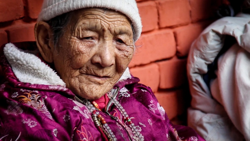 An elderly Tibetan woman joins her community for a cup of tea on a chilly afternoon.