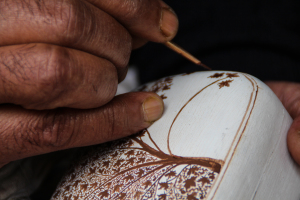 Nagoo adds detail to a paper mache box using a self-made brush.